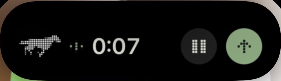 The Dynamic Island held open while recording a voice memo: Shadowfax in dots, a small waveform, the timer at 0:07, a pause button and a green send button.